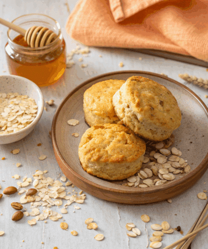 Golden Spelt Breakfast Biscuits on a rustic plate with scattered oats and honey drizzle