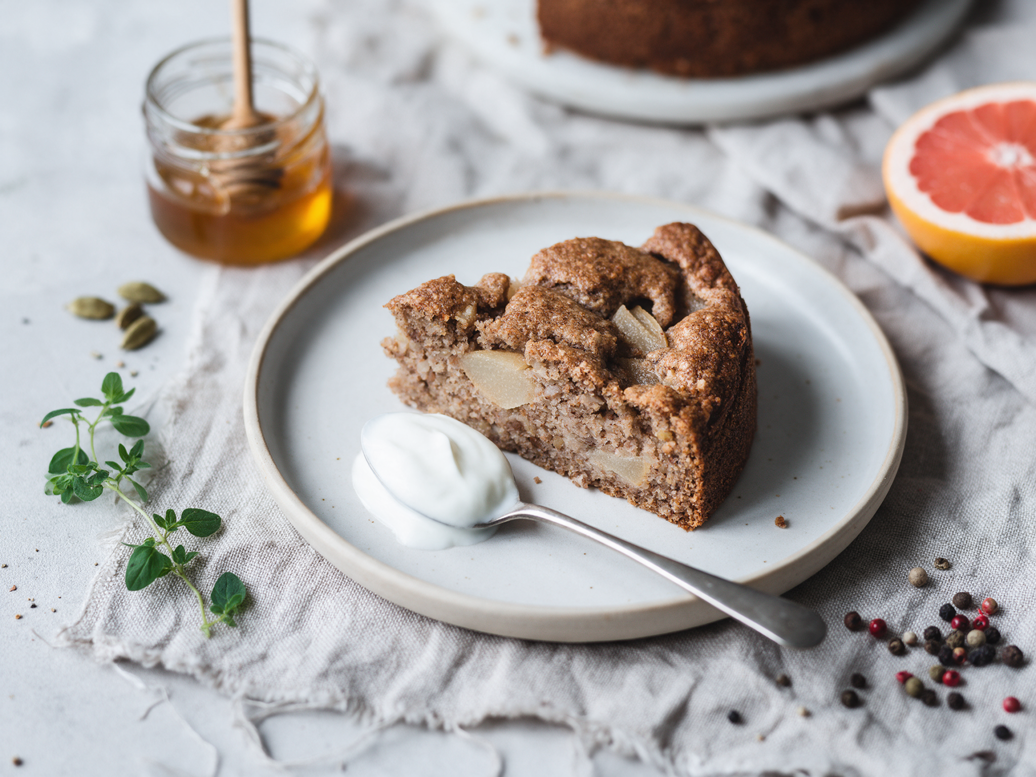 Spelt pear cake slice with pear pieces served with a spoon of yogurt